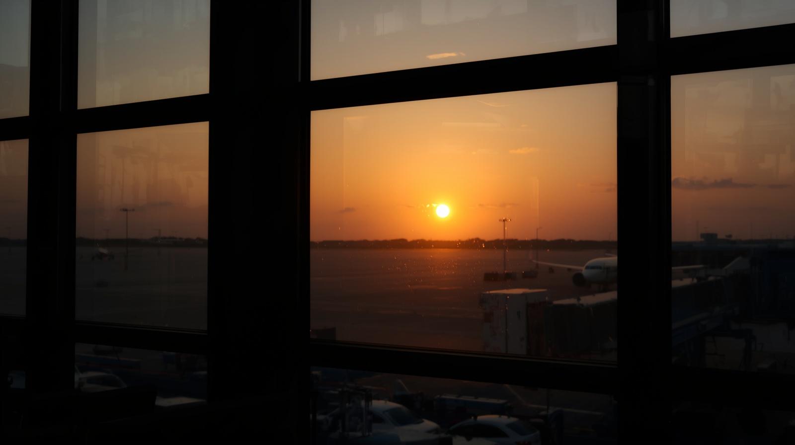 sunrise through airport window, calm reflective tone