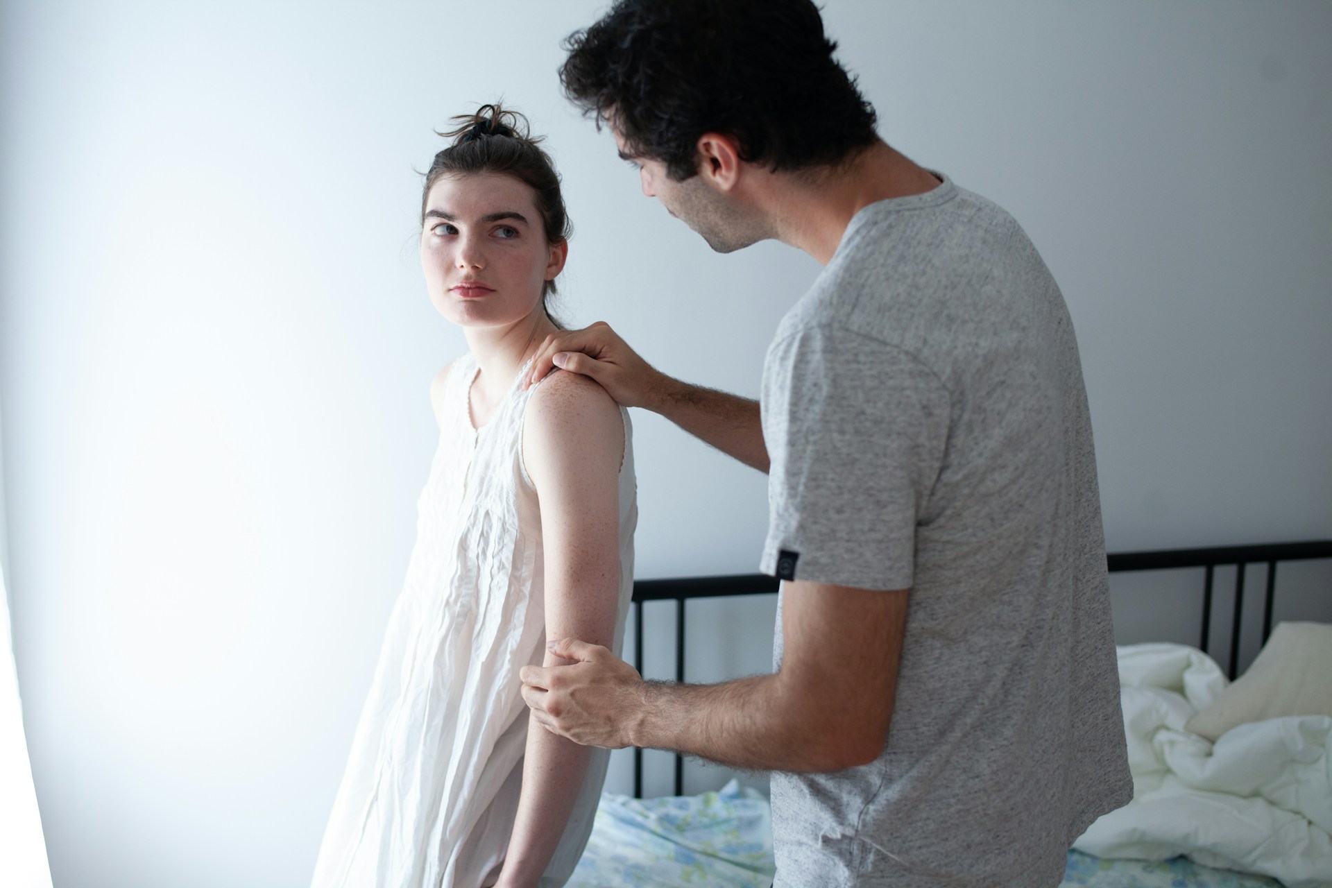 Woman looking emotionally distant as her partner reaches toward her during a tense relationship moment