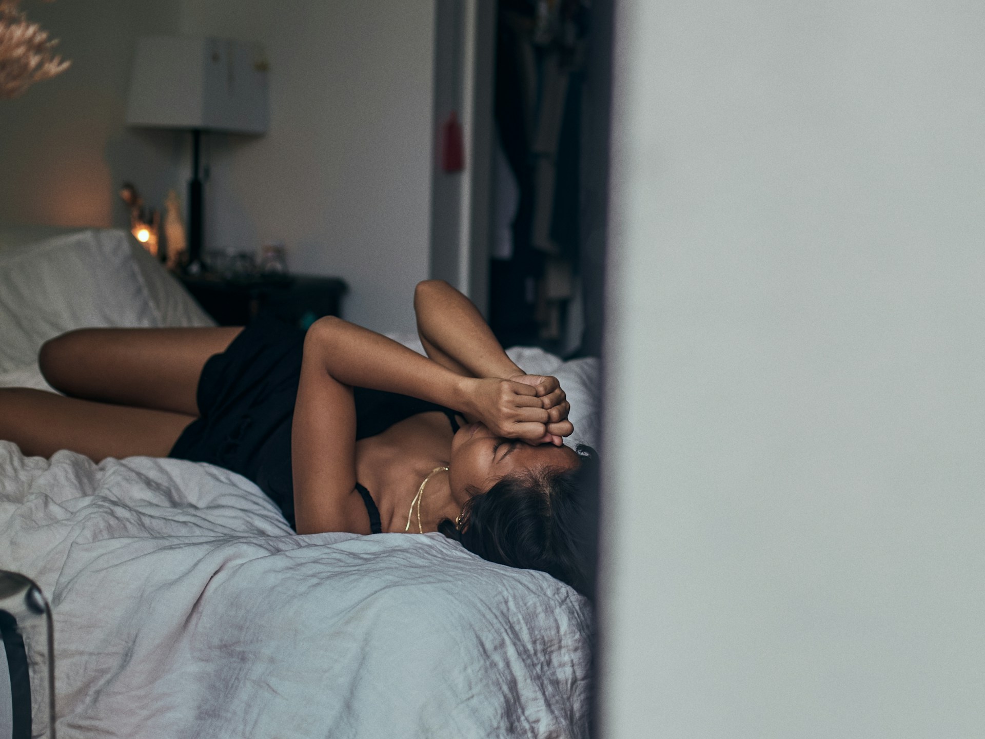 **SEO alt text:** `Woman lying alone on a bed covering her face while struggling with touch starvation and loneliness after a breakup`