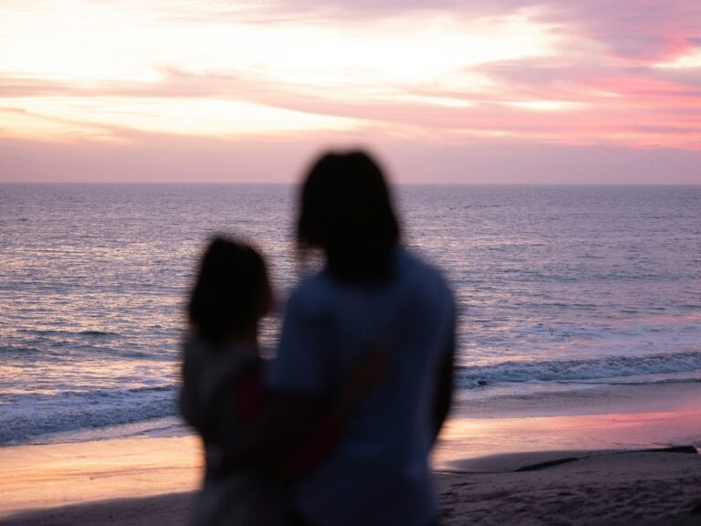 Silhouetted couple standing together on a beach at sunset, representing hope of meeting a future soulmate.